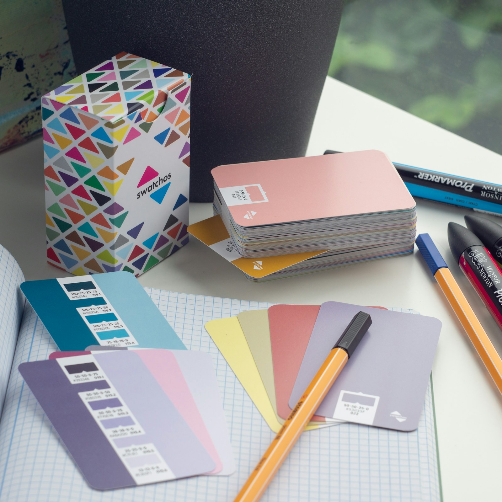 Mesa de design com papéis, cores e materiais gráficos
